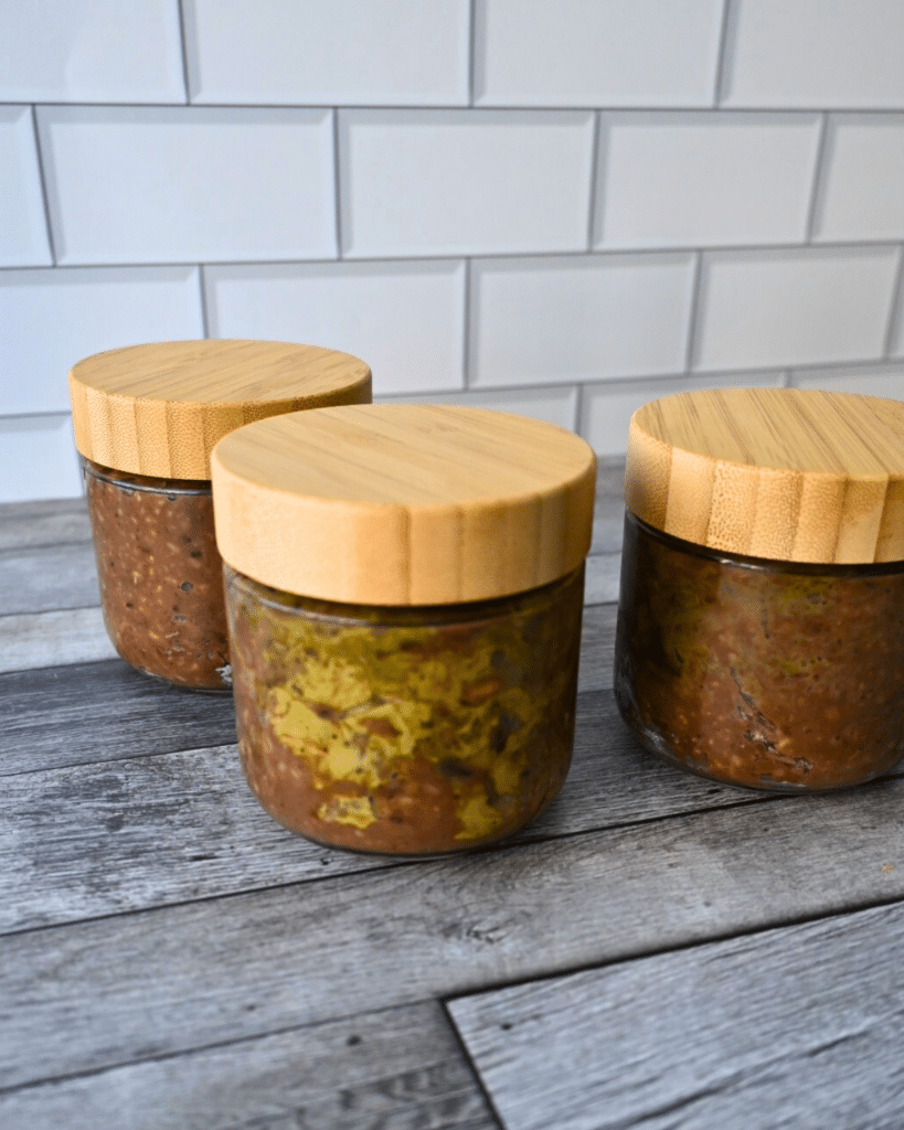 Three jars filled with Dubai chocolate overnight oats with bamboo lids