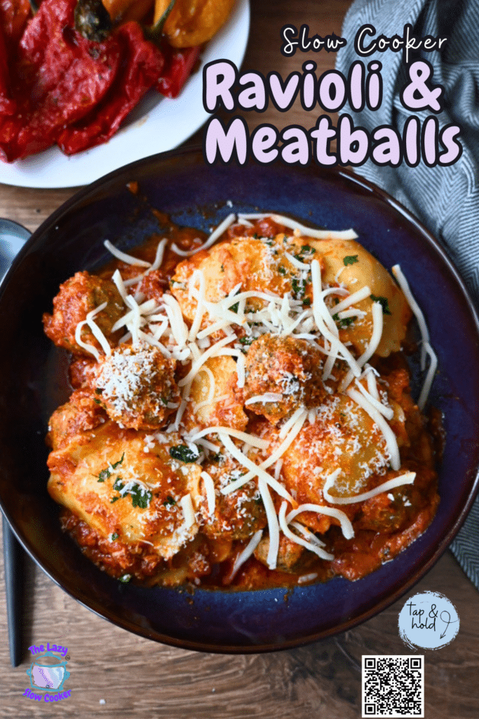 A blue bowl of ravioli and meatballs with marinara, cheese, and parsley on a wood table. Text: “Slow Cooker Ravioli & Meatballs.”.