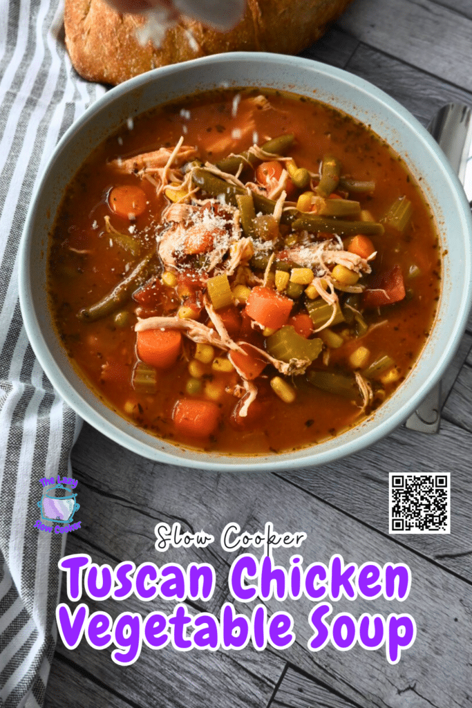 A bowl of chicken vegetable soup with carrots, green beans, corn, and shredded chicken in tomato broth sits by a loaf of bread.