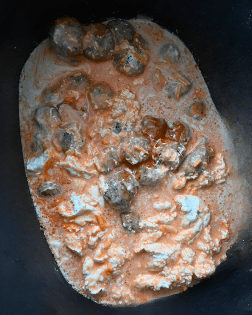 Meatballs covered in creamy orange sauce with melted cheese, cooked together in a slow cooker.