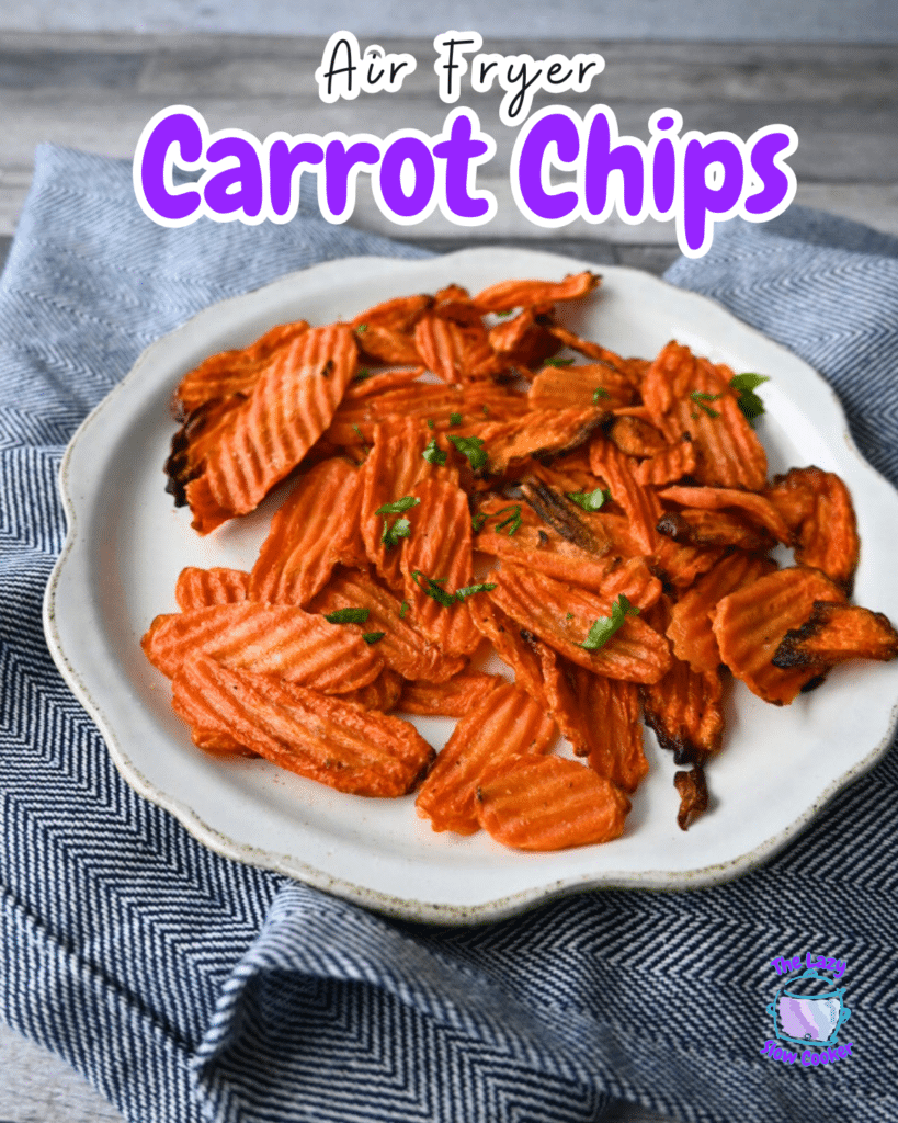 Crinkle-cut carrot chips topped with herbs are served on a white plate over a blue and white cloth. Text reads: Air Fryer Carrot Chips.