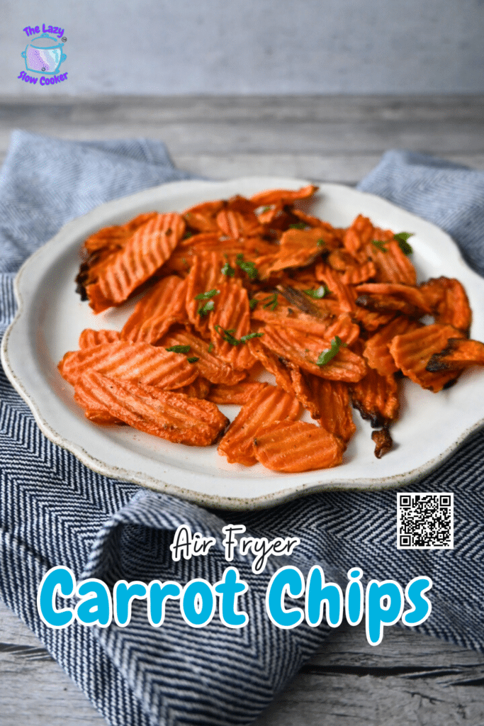 Crinkle-cut carrot chips topped with herbs are served on a white plate over a blue and white cloth. Text reads: Air Fryer Carrot Chips.
