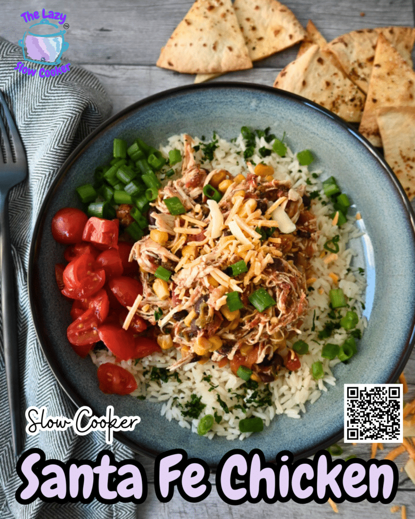 A bowl of slow cooker shredded chicken with corn, black beans, and rice, topped with cheese and green onions, served with tortilla chips.