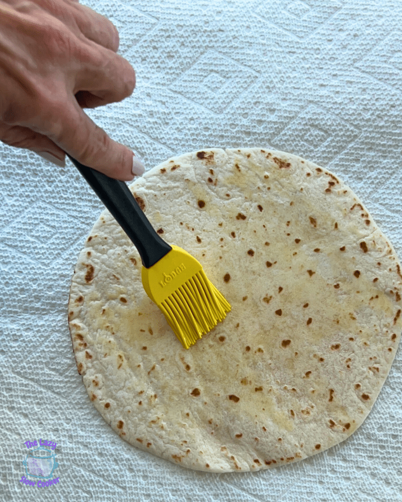 a pastry brush brushing oil on to a tortilla