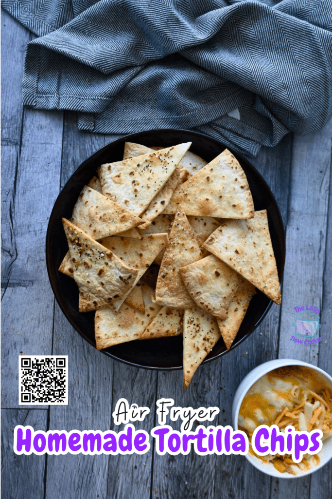 Crispy tortilla chips in a black bowl on a wooden table with a gray cloth. A dip and text: Air Fryer Homemade Tortilla Chips.