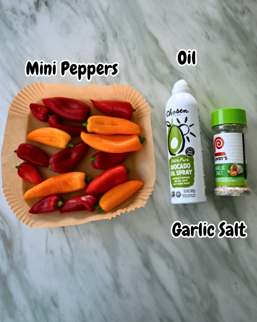 Mini peppers, avocado oil spray, and garlic salt sit labeled on marble—ingredients for air fryer mini peppers.