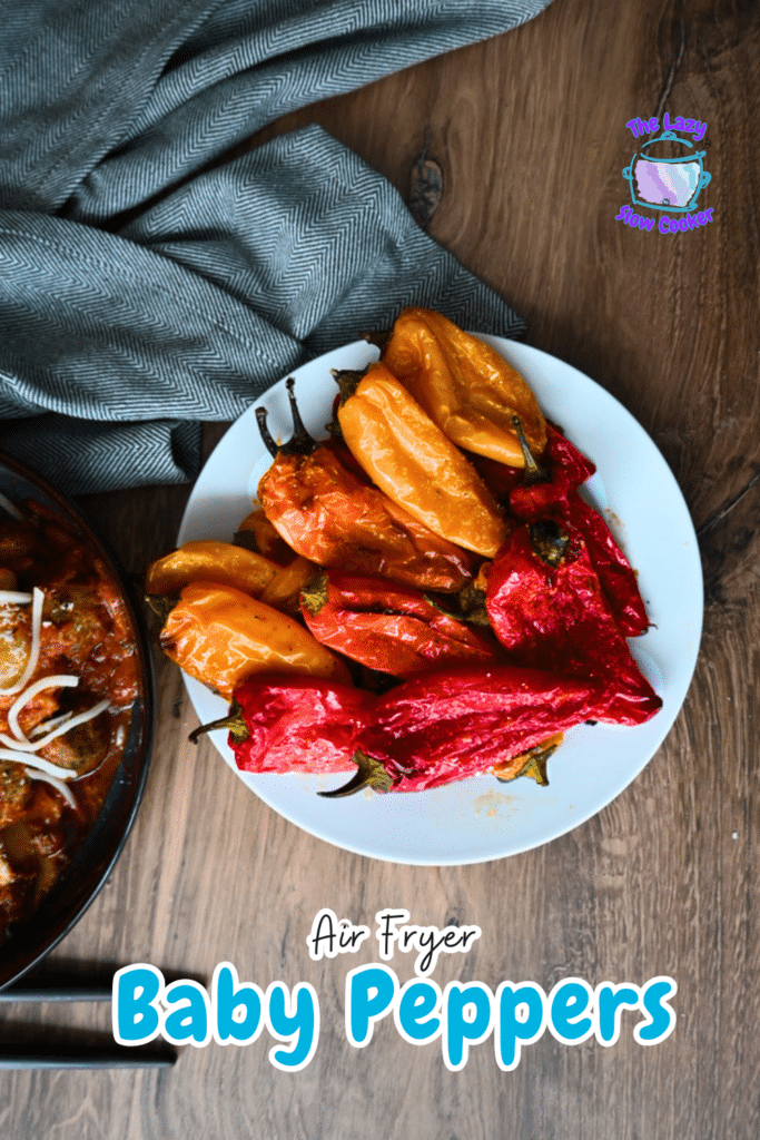 Roasted red and yellow baby peppers on a white plate beside air-fried potatoes; text reads "Air Fryer Baby Peppers.