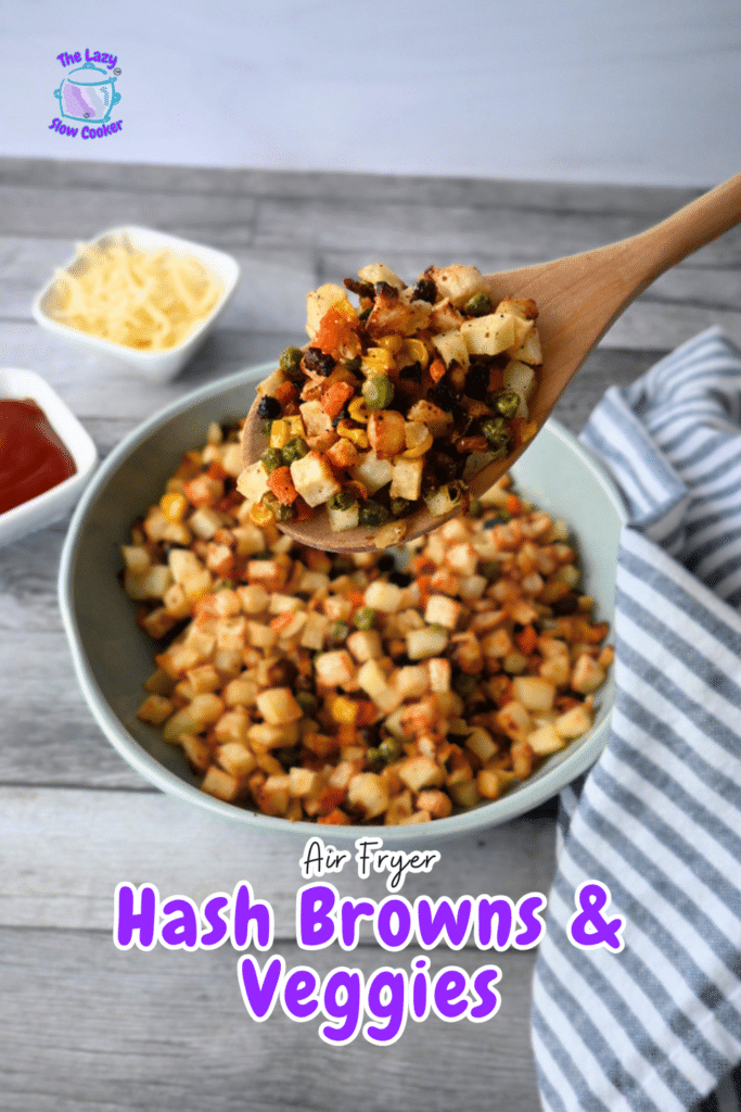 A wooden spoon lifts diced hash browns and vegetables over a bowl, with cheese, ketchup, and a striped cloth nearby. Text: Air Fryer Hash Browns & Veggies.