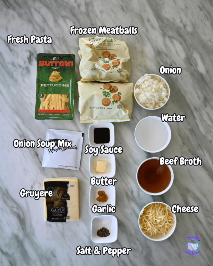 A marble surface displays labeled ingredients for French Onion Meatball Pasta, including pasta, meatballs, onions, cheese, and seasonings.
