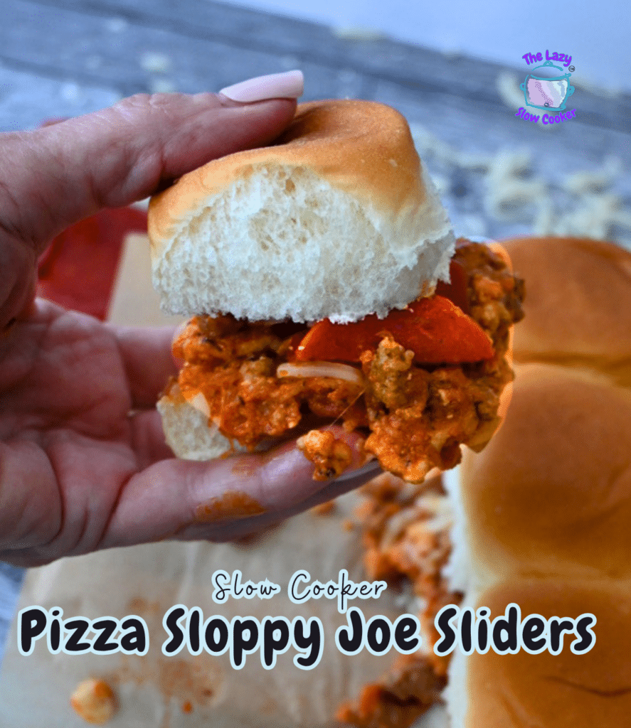 A hand holds a pizza sloppy joe slider filled with saucy meat and pepperoni; two more sliders sit on a tray. Text: Slow Cooker Pizza Sloppy Joe Sliders.