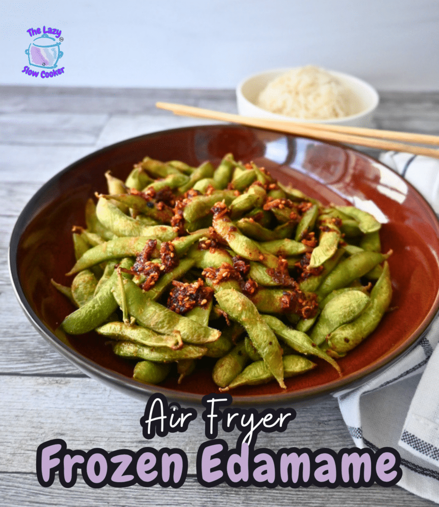 Seasoned edamame in a red bowl sits on a table, with rice and chopsticks behind it. Text says "Air Fryer Frozen Edamame.