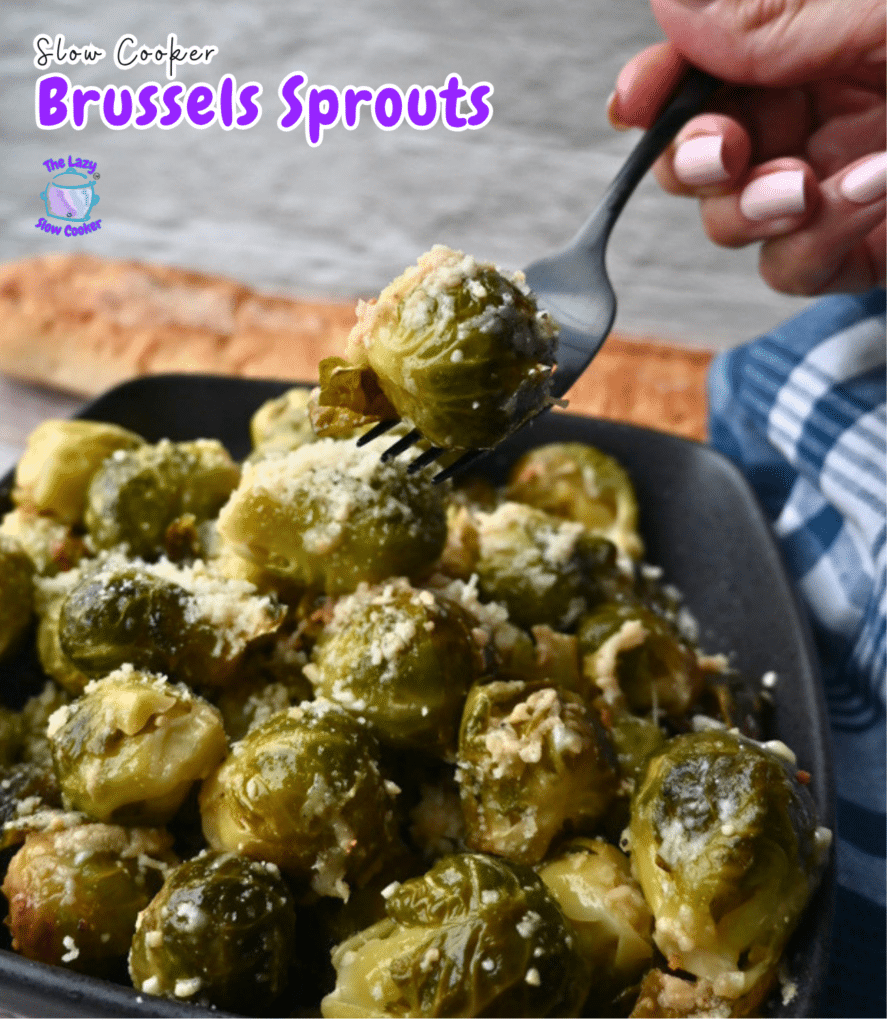 A hand lifts a Brussels sprout on a fork above a plate of cheesy slow cooker Brussels sprouts. Text reads "Slow Cooker Brussels Sprouts.
