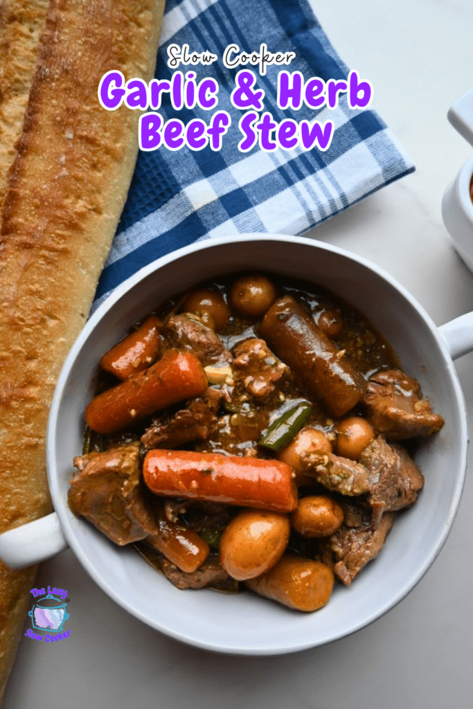 A bowl of garlic herb beef stew with carrots, potatoes, and green beans sits near bread and a blue checkered napkin. Recipe title visible.