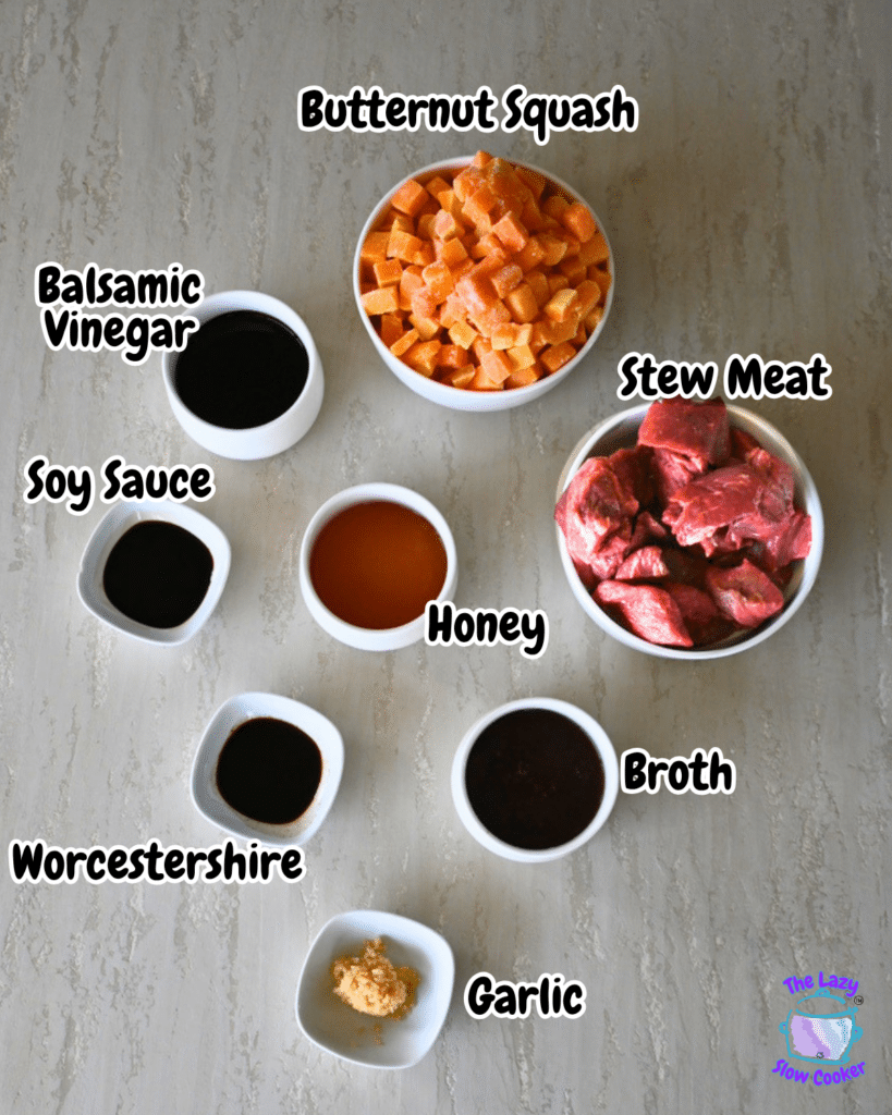 A top-down photo shows bowls filled with the ingredients for honey balsamic beef and butternut squash. The bowls hold stew meat, chunks of butternut squash, broth, balsamic vinegar, soy sauce, Worcestershire sauce, honey, and minced garlic. All are arranged neatly on a light-colored surface with clear labels for each ingredient.