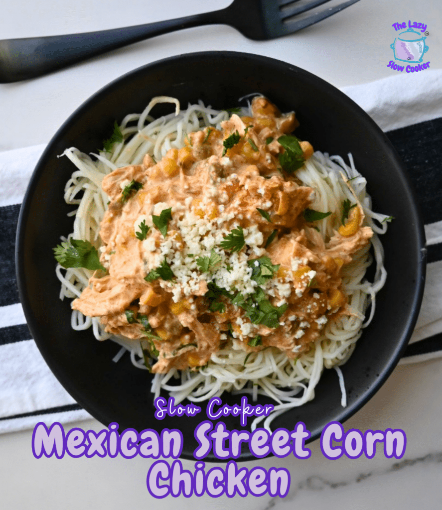 A black bowl holds noodles topped with creamy chicken, corn, cilantro, and cheese. The dish is labeled “Slow Cooker Mexican Street Corn Chicken.” A fork and napkin rest next to the bowl.
